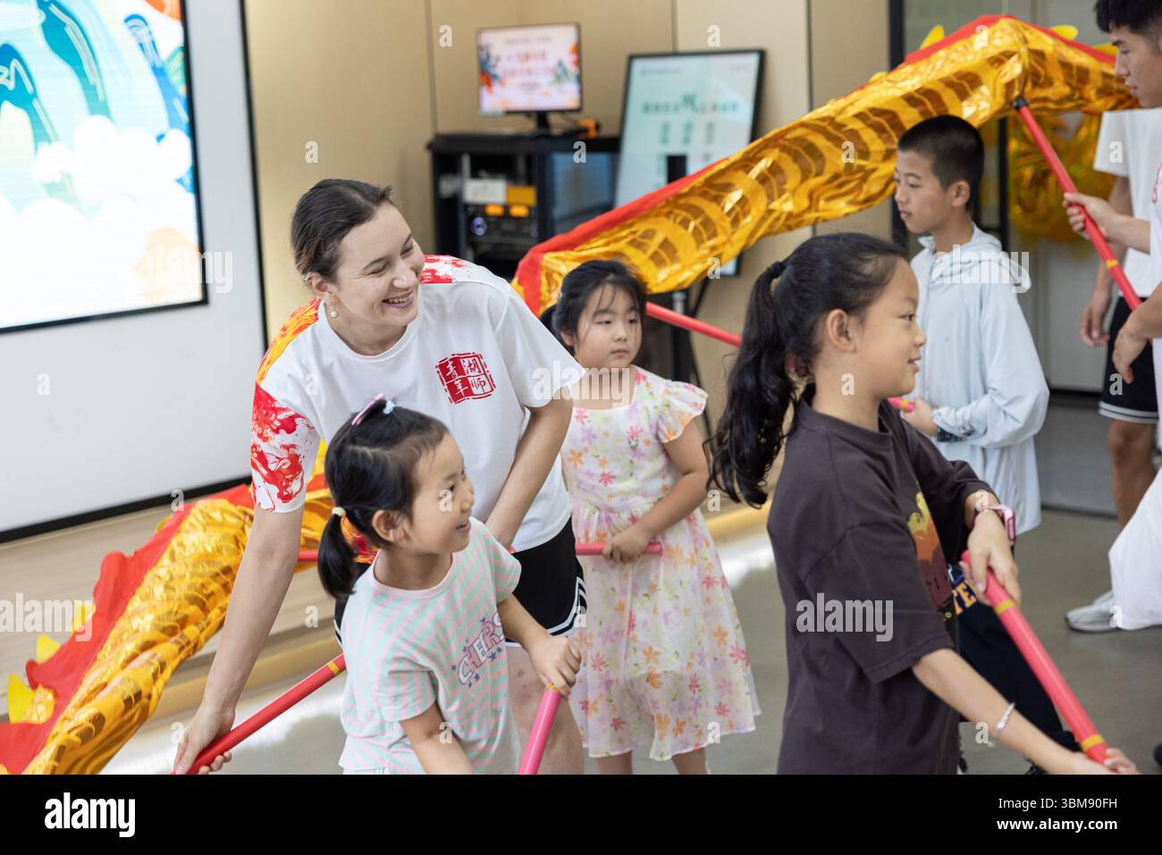 (250625) – HUZHOU, 25. Juni 2025 (Xinhua) – Gubaidullina Shakhnaz Evgenevna erlebt Drachentanz mit Kindern in der Stadt Huzhou, ostchinesischer Provinz Zhejiang, am 8. Juli 2024. Gubaidullina Shakhnaz Evgenjewna, ein russisches Mädchen, das in Huzhou studiert, hat sich in den sozialen Medien Chinas in letzter Zeit verbreitet. Sie hat gerade an der Huzhou University einen Bachelor-Abschluss gemacht. Am 23. Juni wurde sie Zeuge einer älteren Frau, die ins Wasser fiel, als sie auf ihrer Abschlussreise nach Shaoxing in der Provinz Zhejiang reiste. Sie zögerte nicht, ins Wasser zu springen und versuchte, sie zu retten, die s war Stockfoto