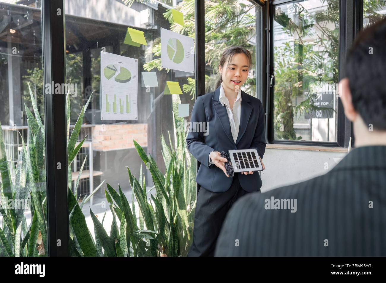 Umweltfreundliche Initiativen und Datenpräsentation. Eine Geschäftsfrau teilt Erkenntnisse über Nachhaltigkeitsstrategien mit Visuals und Geräten. Stockfoto