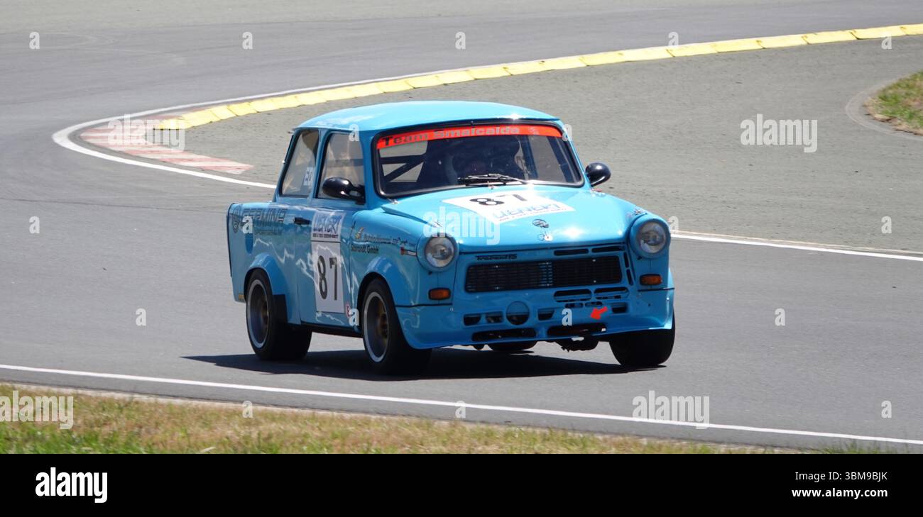 Ein leuchtend blauer Trabant-Rennwagen, der auf der Schleizer Dreieck-Rennstrecke in Deutschland in Aktion gehalten wird. Stockfoto