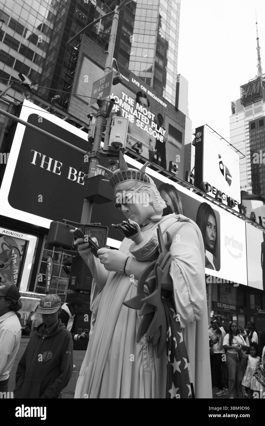 Straßenkünstler verkleidet als Freiheitsstatue, überprüft sein Smartphone - Times Square - New-York City, Juni 2025 Stockfoto