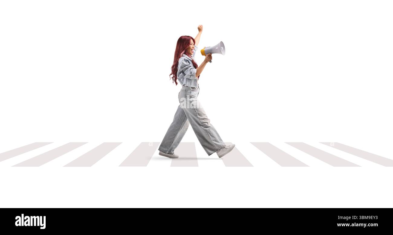 Asiatische Frau, die auf Zebraüberquerung läuft und mit einem Megaphon spricht, isoliert auf weißem Hintergrund Stockfoto