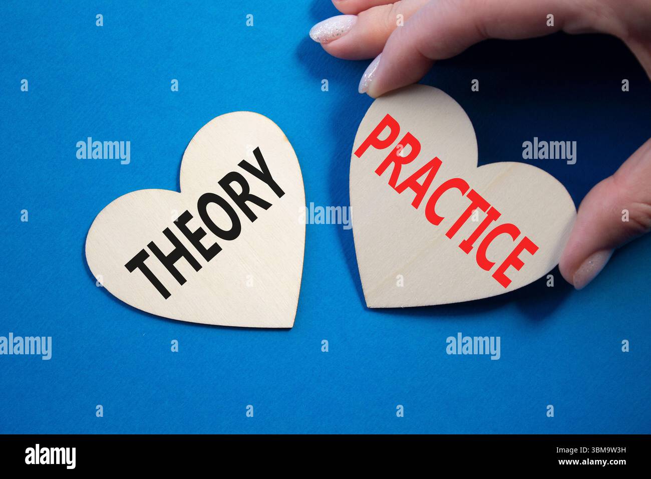 Theorie- oder Praxissymbol. Konzeptwort Theorie oder Praxis auf hölzernen Herzen. Geschäftsmann Hand. Wunderschöner blauer Hintergrund. Business und Theorie oder Praxis Stockfoto