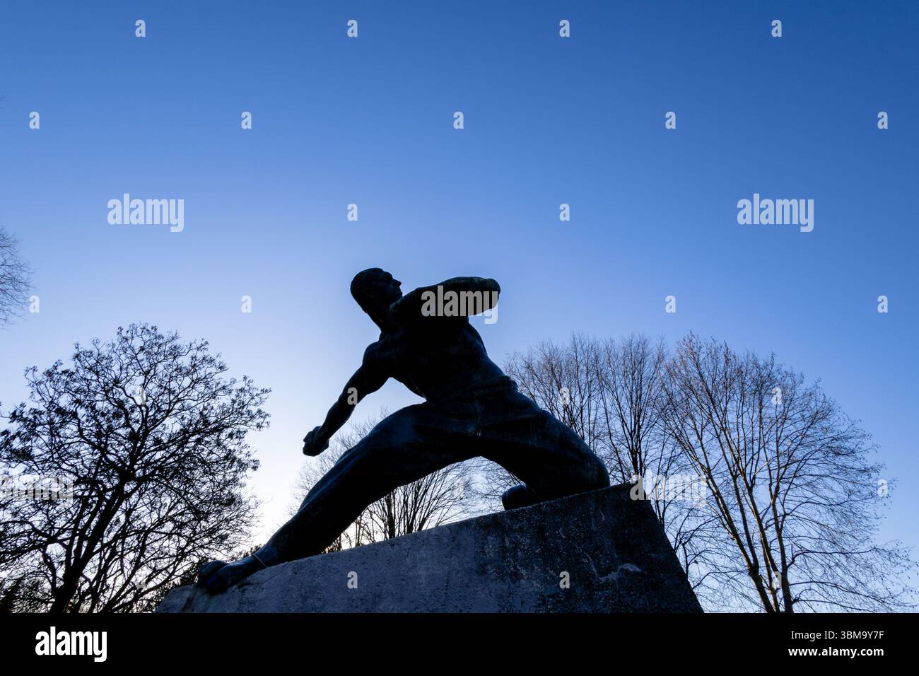 NOVA GORICA, KROATIEN, 03.18.2025: Ein dramatisches Foto einer Kriegerstatue in einem Park, gesehen vor einem sonnigen und klaren Himmel mit Hintergrundbeleuchtung. Das Bild evozieren Stockfoto