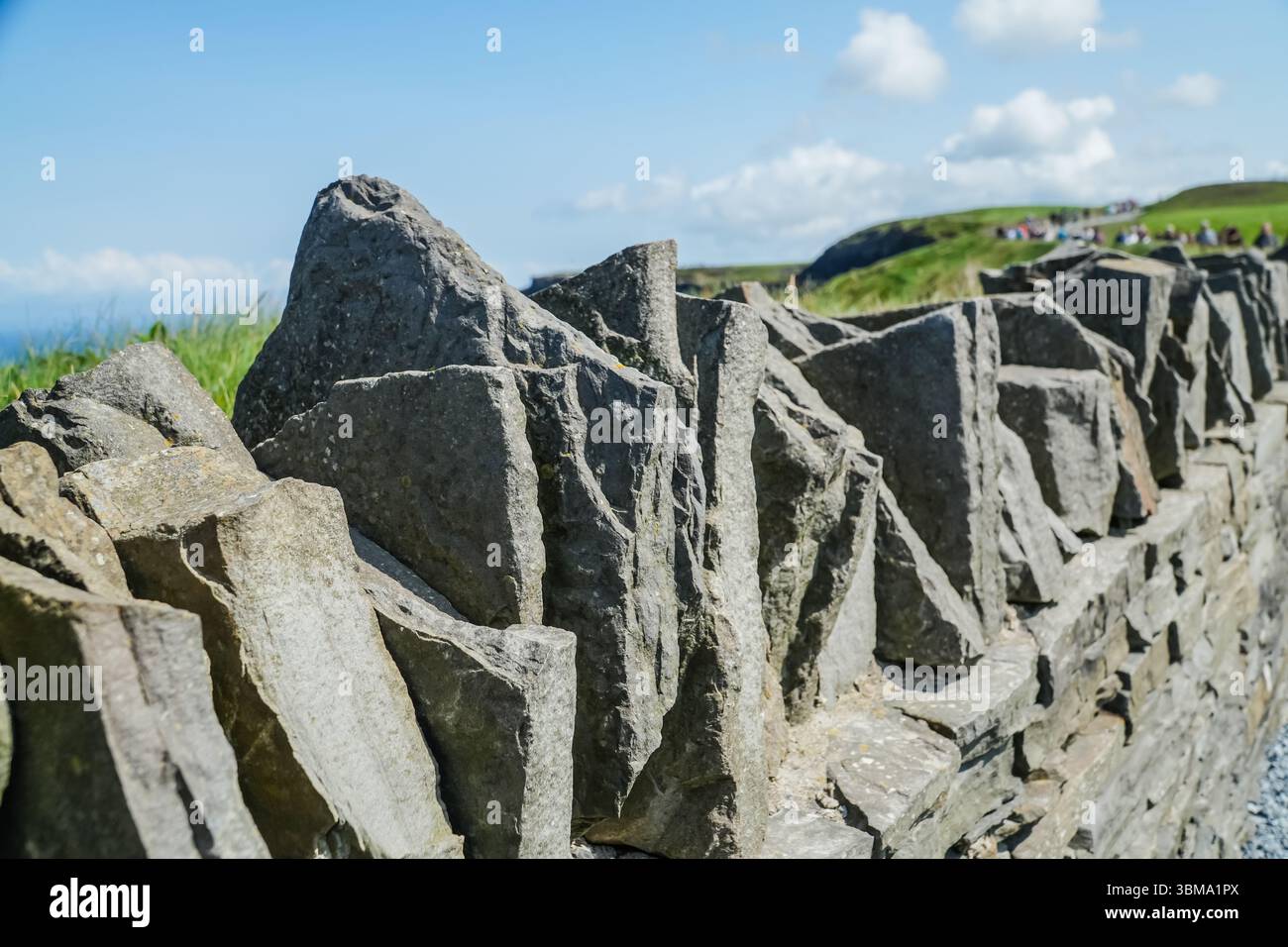 Detail einer zerklüfteten Steinmauer in der Nähe von Cliffs of Moher, Irland. Nahaufnahme der natürlichen Felswand entlang eines malerischen Pfades. Stockfoto