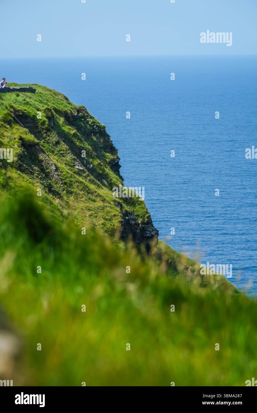 Cliffs of Moher, Irlands dramatische Küstenklippen mit Blick auf das weite Meer. Umfasst eine kleine Person am Rand, fördert Waage und Isolation. Stockfoto