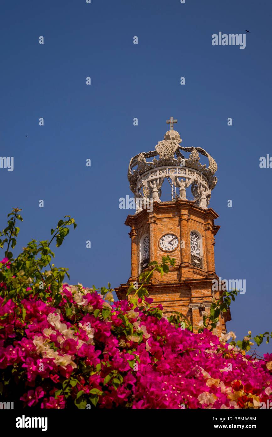 Blick auf die Kirche unserer Lieben Frau von Guadalupe in Puerto Vallarta, Bundesstaat Jalisco, Mexiko mit Bougainville-Blumen im Vordergrund. Stockfoto