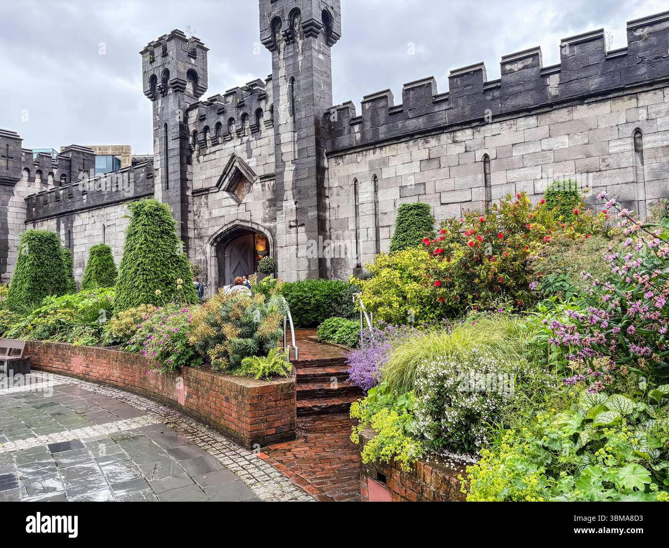 Dubh Linn Garden bietet wunderschöne Staudenpflanzungen, die an historische Steinmauern und Türme hinter Dublin Castle, einer beliebten Besucherattraktion, grenzt. Stockfoto