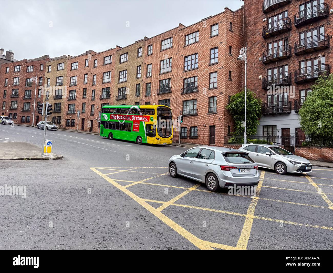 Ein Doppeldeckerbus und Autos auf einer Straße in Dublin, Irland. Mit Ziegelgebäuden und Ampeln in einer urbanen Szene. Stockfoto