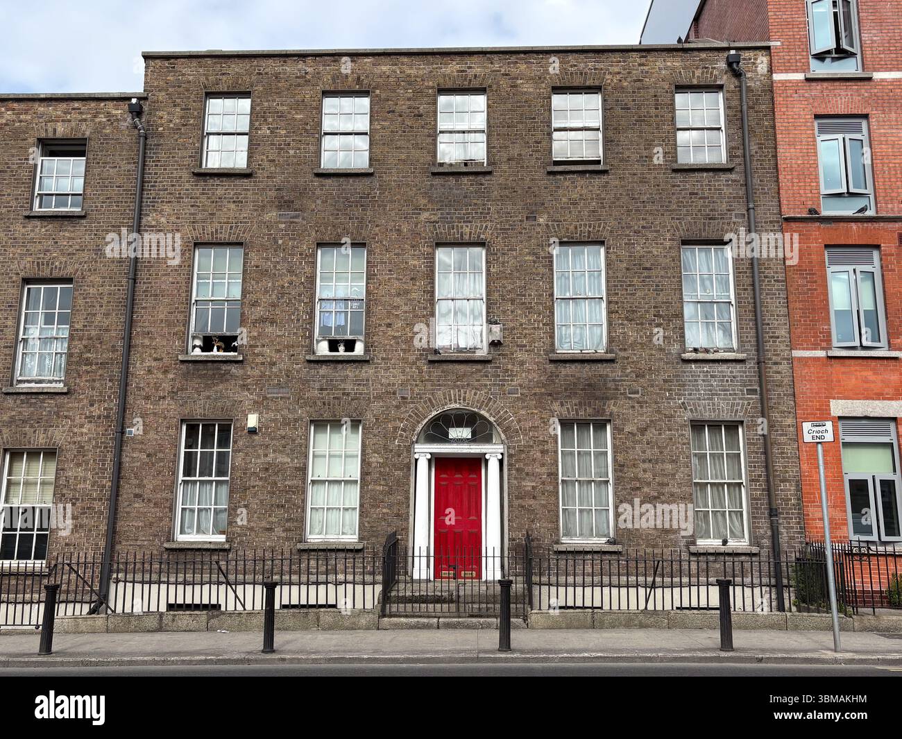 Architektur im georgischen Stil in Dublin, Irland. Außenfassade eines traditionellen Backsteingebäudes mit hohen Fenstern und einer roten Tür. Stockfoto