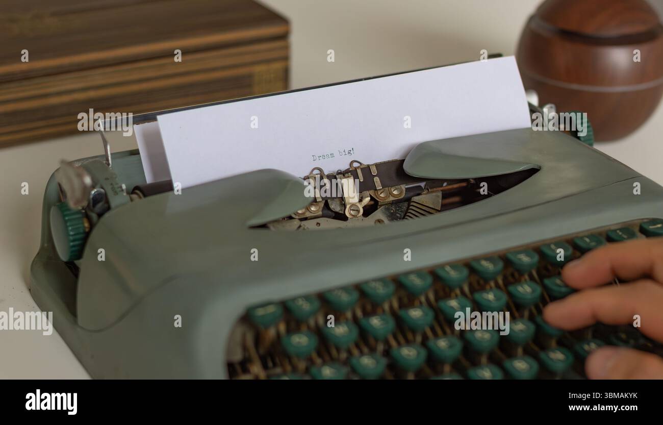 Writer verwendet eine Vintage-Schreibmaschine, um den Motivationssatz „Dream Big“ einzugeben und andere dazu zu inspirieren, ehrgeizige Ziele und Ziele zu verfolgen Stockfoto