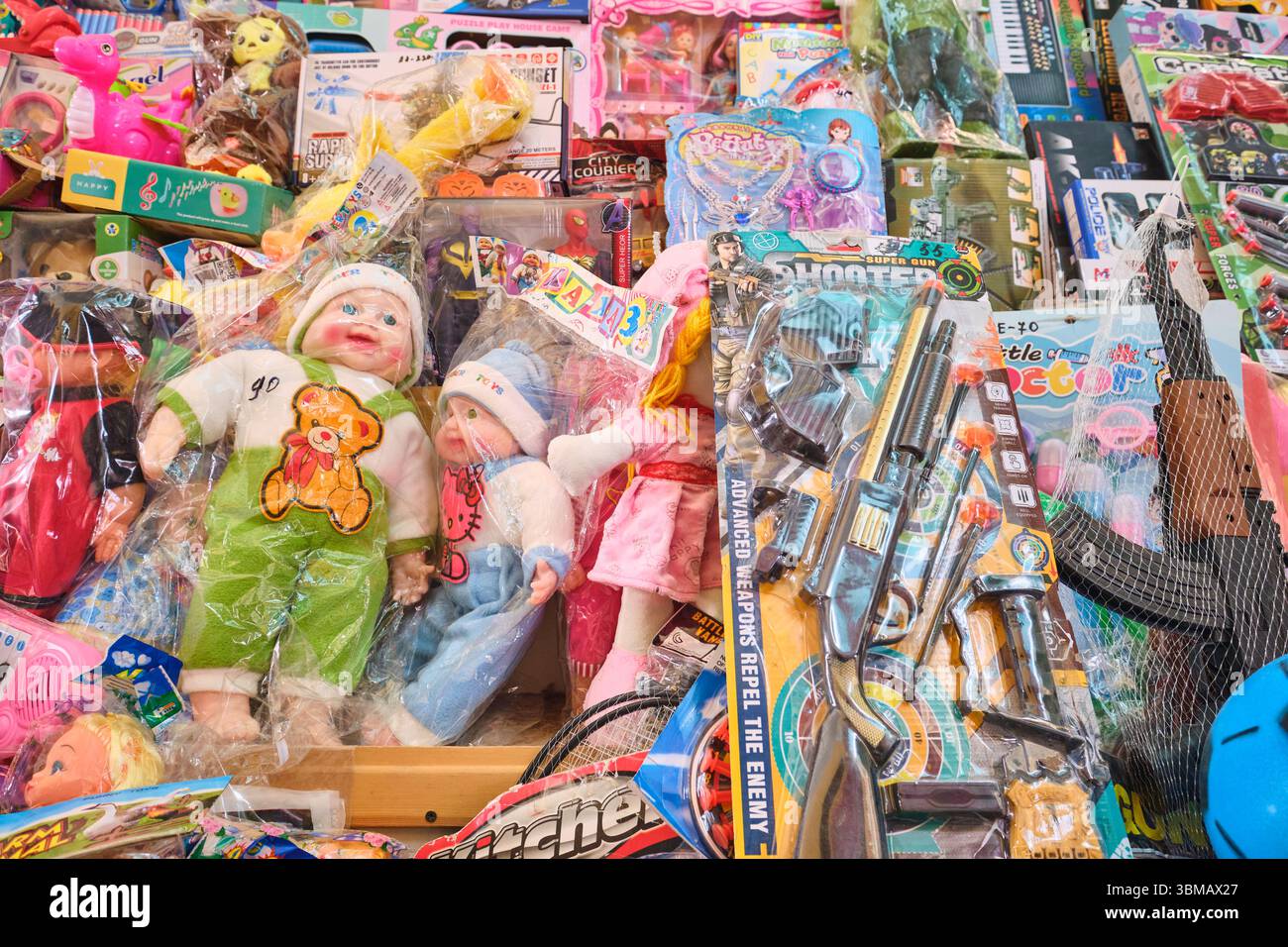 Ein großer Haufen billiger Gegenstände, darunter Babypuppen und Waffen. Spielzeug zum Verkauf auf dem lokalen Eski Basar, Markt. In Qarshi, Usbekistan. Stockfoto