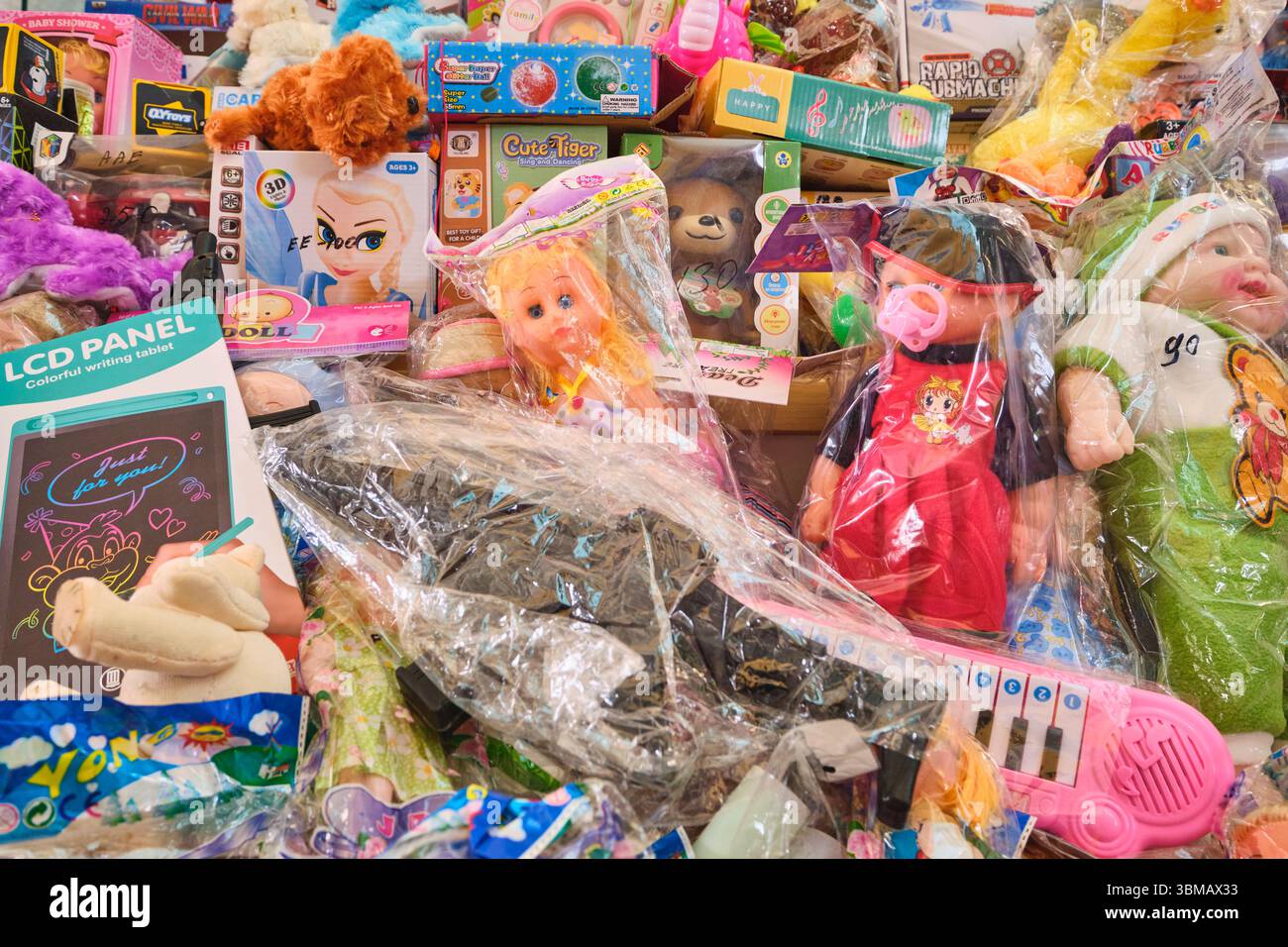 Ein großer Stapel von Gegenständen zum Verkauf, darunter Puppen, eine große Pistole. Spielzeug zum Verkauf auf dem lokalen Eski Basar, Markt. In Qarshi, Usbekistan. Stockfoto