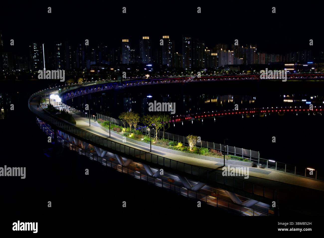 Sejong City, Südkorea - 12. Juni 2025: Ein nächtlicher Blick auf die kreisförmige Geumgang Fußgängerbrücke zeigt den beleuchteten Weg, die grüne Landschaft und Stockfoto
