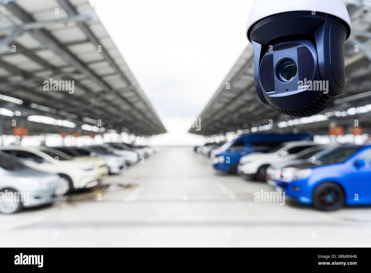Überwachungskamera überwacht einen modernen Parkplatz im Freien. Autos, die in Reihen unter einer Dachkonstruktion des Sonnenkollektors geparkt werden. Konzept der Überwachung, der Sicherheit, Stockfoto