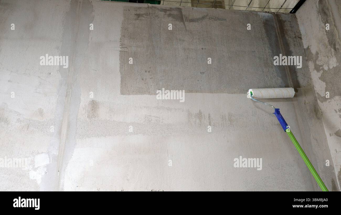 Abdichtungsverfahren, Aufbringen einer Abdichtungsmembran auf eine Betonwand mit einer Malerwalze Stockfoto