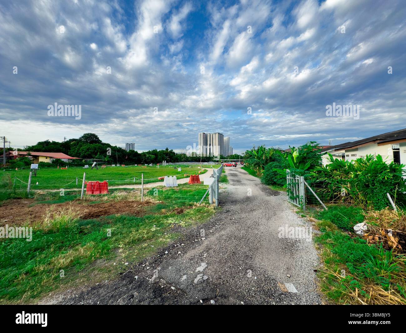 Weitwinkelansicht eines leeren Reitfeldes, aufgenommen vom vorderen Zaun, mit einem klaren Himmel und einem Gebäude im Hintergrund. - Smartphone-aufgenommenes Stockfoto