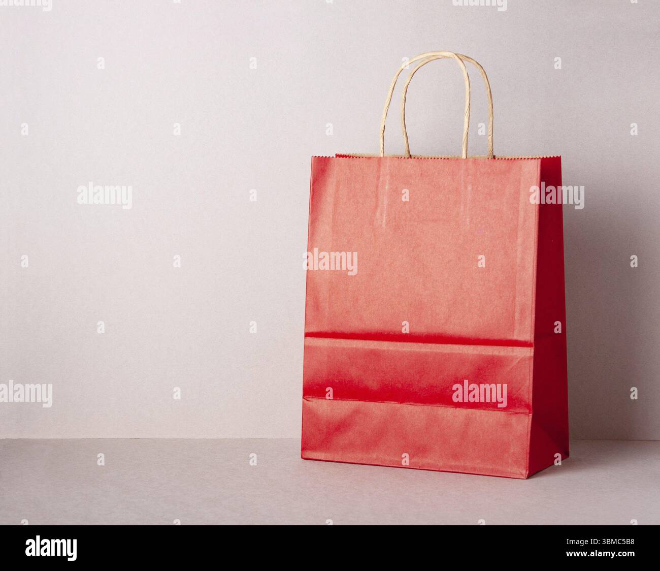 Geschenktüte aus rotem Papier, beigefarbener Hintergrund, Modell, Kopierraum, Boxtag Stockfoto