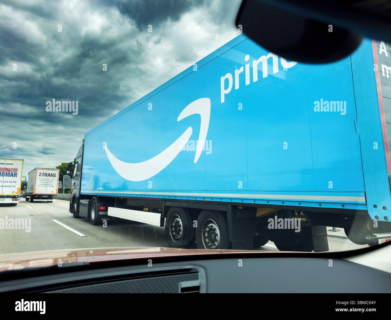 Frankfurt, Deutschland - 7. Mai 2025: Großer Amazon Prime Truck mit blauem Anhänger mit dem Prime-Logo fährt auf einer stark befahrenen deutschen Autobahn unter dramatischem Hintergrund Stockfoto