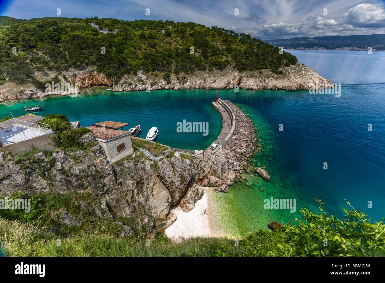 Blick von oben auf das Panorama der Stadt Vrbnik und einen kleinen versteckten Strand zwischen hohen Felsen, eine Touristenattraktion versteckter Kieselstrand auf der Insel KR Stockfoto