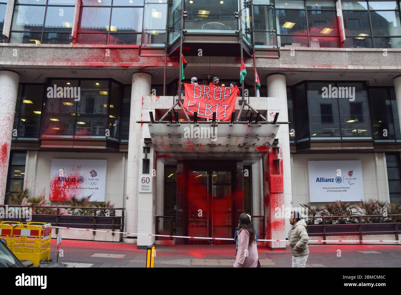 London, Großbritannien. März 2025. Aktivisten der Gruppe Palestine Action klettern auf den Eingang der Allianz-Büros in der City of London, nachdem sie das Gebäude mit roter Farbe besprüht haben. Die Aktivisten rufen den Versicherungsriesen auf, Verbindungen zum Waffenunternehmen Elbit Systems zu unterbrechen. Quelle: Vuk Valcic/Alamy Live News Stockfoto