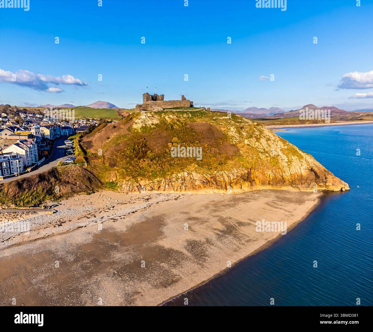 Ein Blick aus der Vogelperspektive auf den Weststrand und die Ruinen der Burg oberhalb von Criccieth, Wales im Frühling Stockfoto