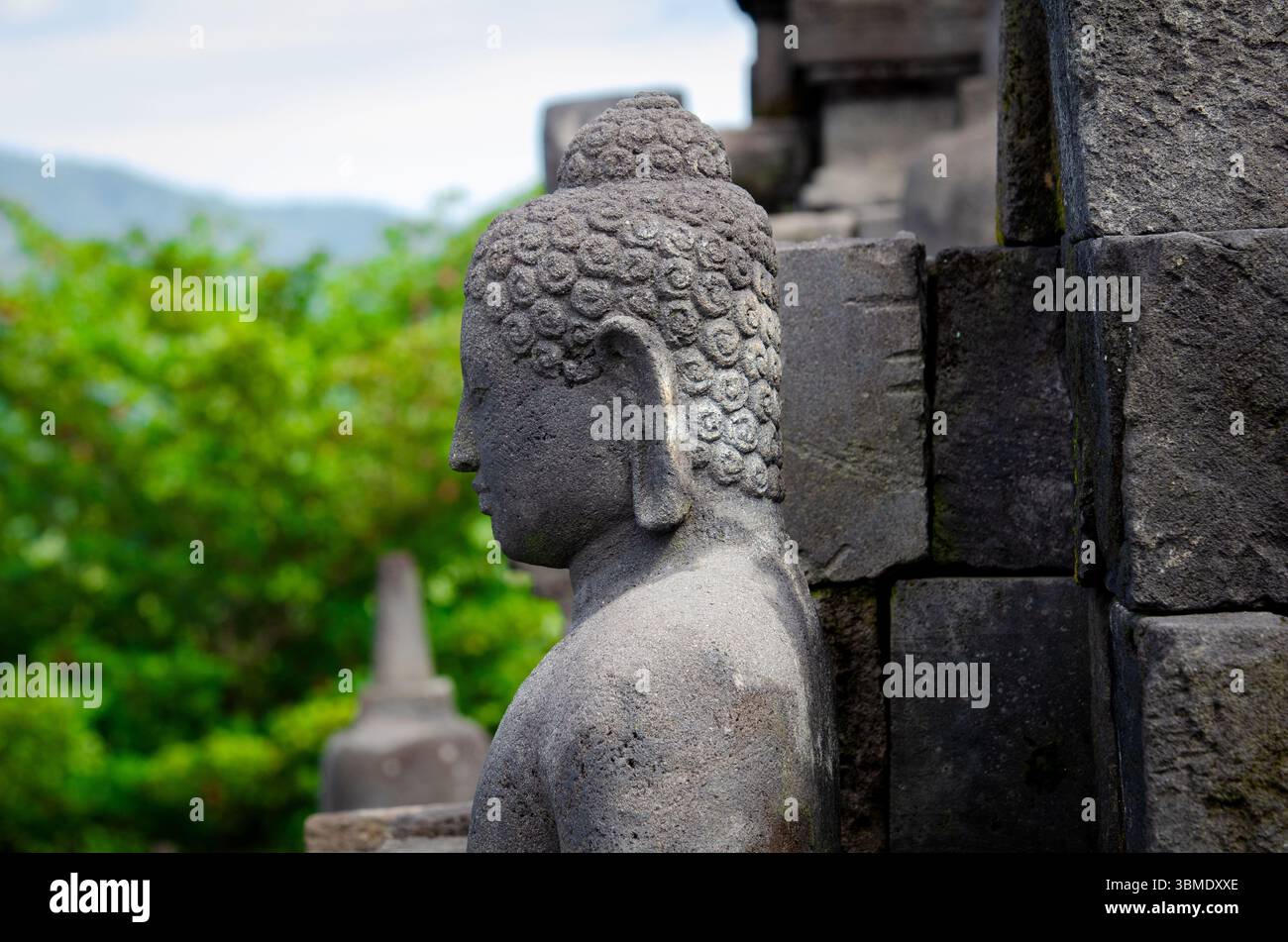 Die antike Buddha-Statue befindet sich inmitten von Steinruinen am Borobudur-Tempel, einem UNESCO-Weltkulturerbe. Stockfoto