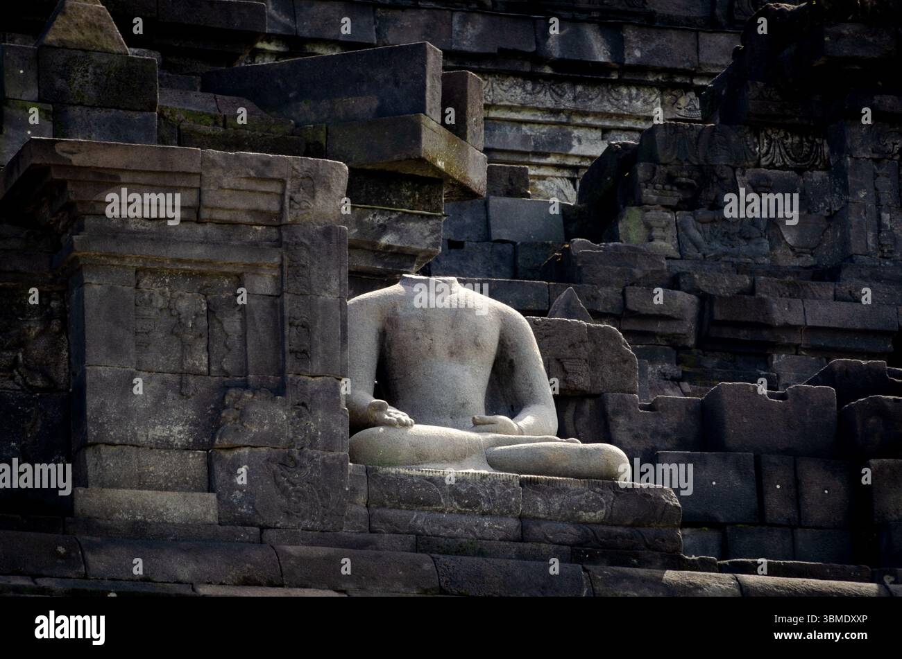 Antike kopflose Buddha-Statue, die sich zwischen Steinruinen am Borobudur-Tempel befindet, ein UNESCO-Weltkulturerbe. Stockfoto