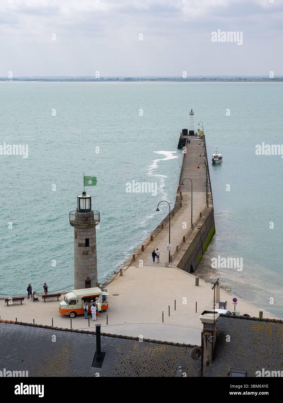 CANCALE, FRANKREICH – 17. MAI 2025: Erhöhter Blick auf den Leuchtturm aus Stein und den Bootsanleger in Cancale, Bretagne, mit Menschen, die entlang des Piers spazieren gehen und einen imbisssteg besuchen Stockfoto
