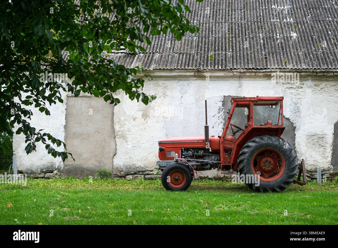Roter Traktor vor der ländlichen Scheunenwand Stockfoto