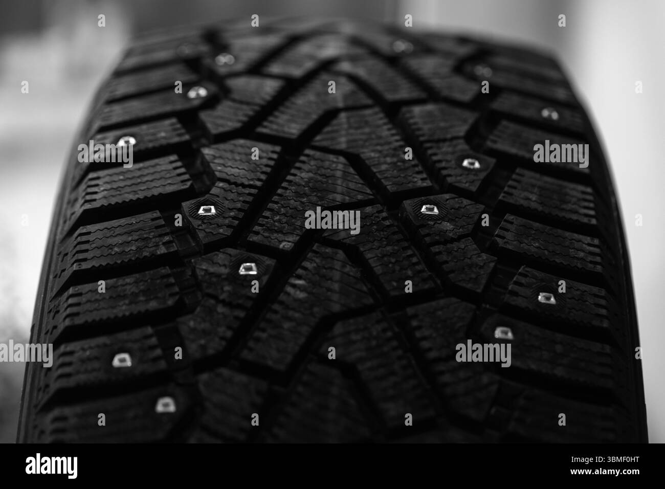Eine detaillierte Nahaufnahme eines Winterreifens mit seinem komplizierten Profilprofil und den eingebetteten Metallstollen, die das Design für überragende Traktion betonen Stockfoto