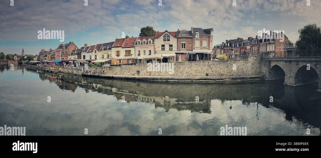 Weitwinkelblick mit malerischer Uferarchitektur, einer bezaubernden Steinbrücke und ruhigem Wasser. Stockfoto