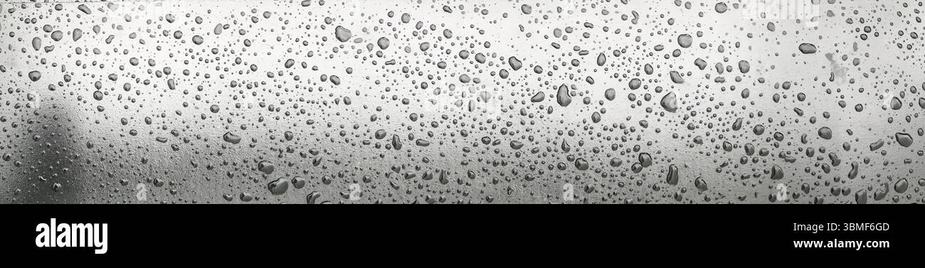 Ein Panorama mit Wassertropfen auf einer reflektierenden Oberfläche, das an ruhige Einfachheit erinnert. Die monochromen Töne verstärken den strukturierten Glanz des Sur Stockfoto