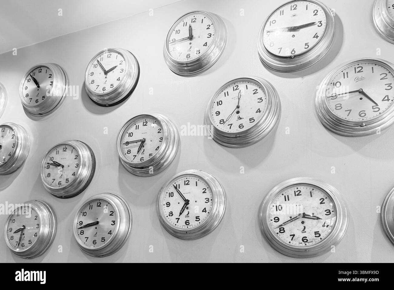 Uhren an der Wand, die alle verschiedene Zeiten anzeigen Stockfoto
