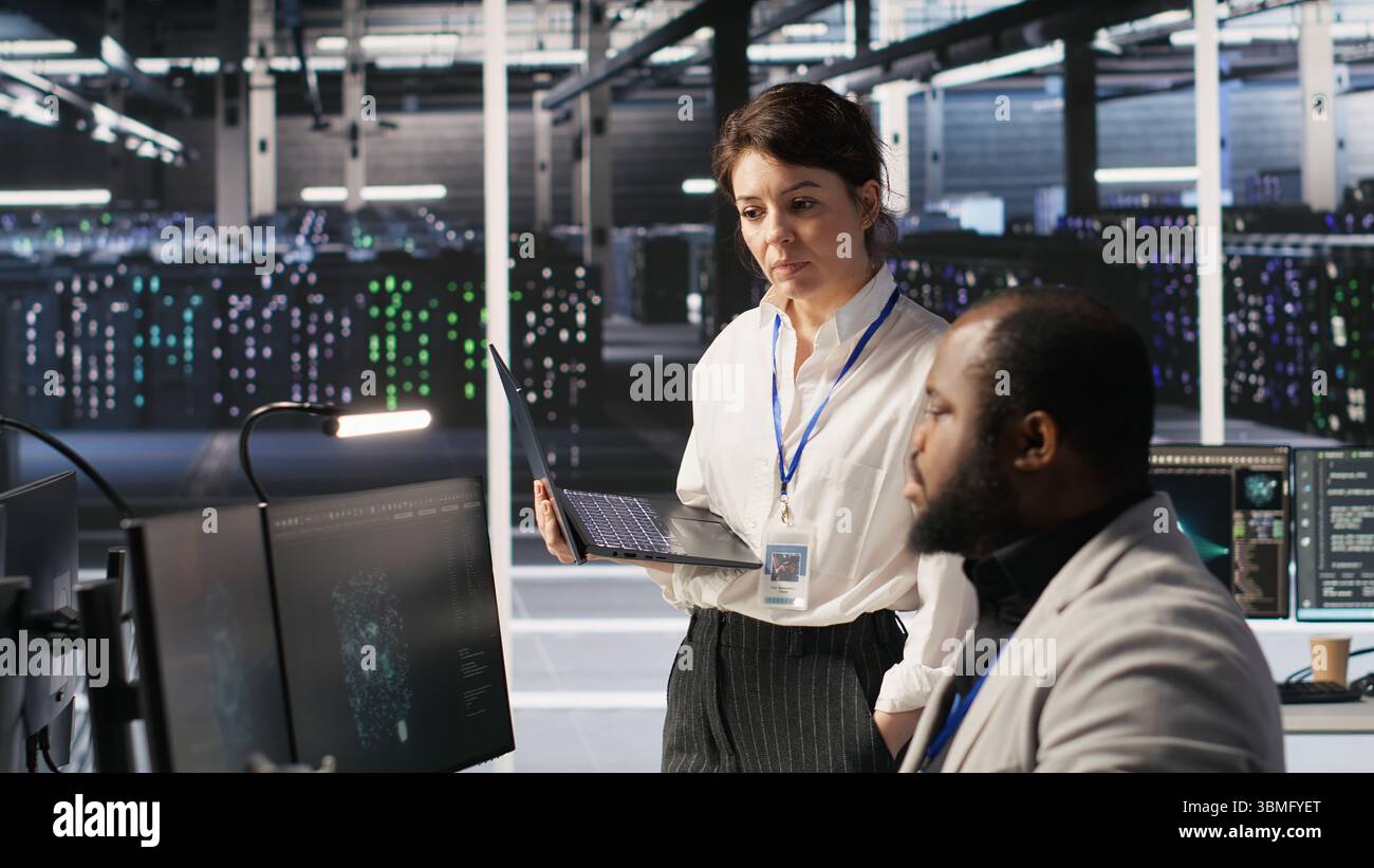 Zufriedener Rechenzentrumsmanager gibt dem Entwickler von Software für neuronale Netzwerke auf dem Computer positives Feedback. Fröhlicher Vorgesetzter zufrieden mit der Arbeit der Mitarbeiter bei der Implementierung von KI im Serverraum, Kamera A Stockfoto