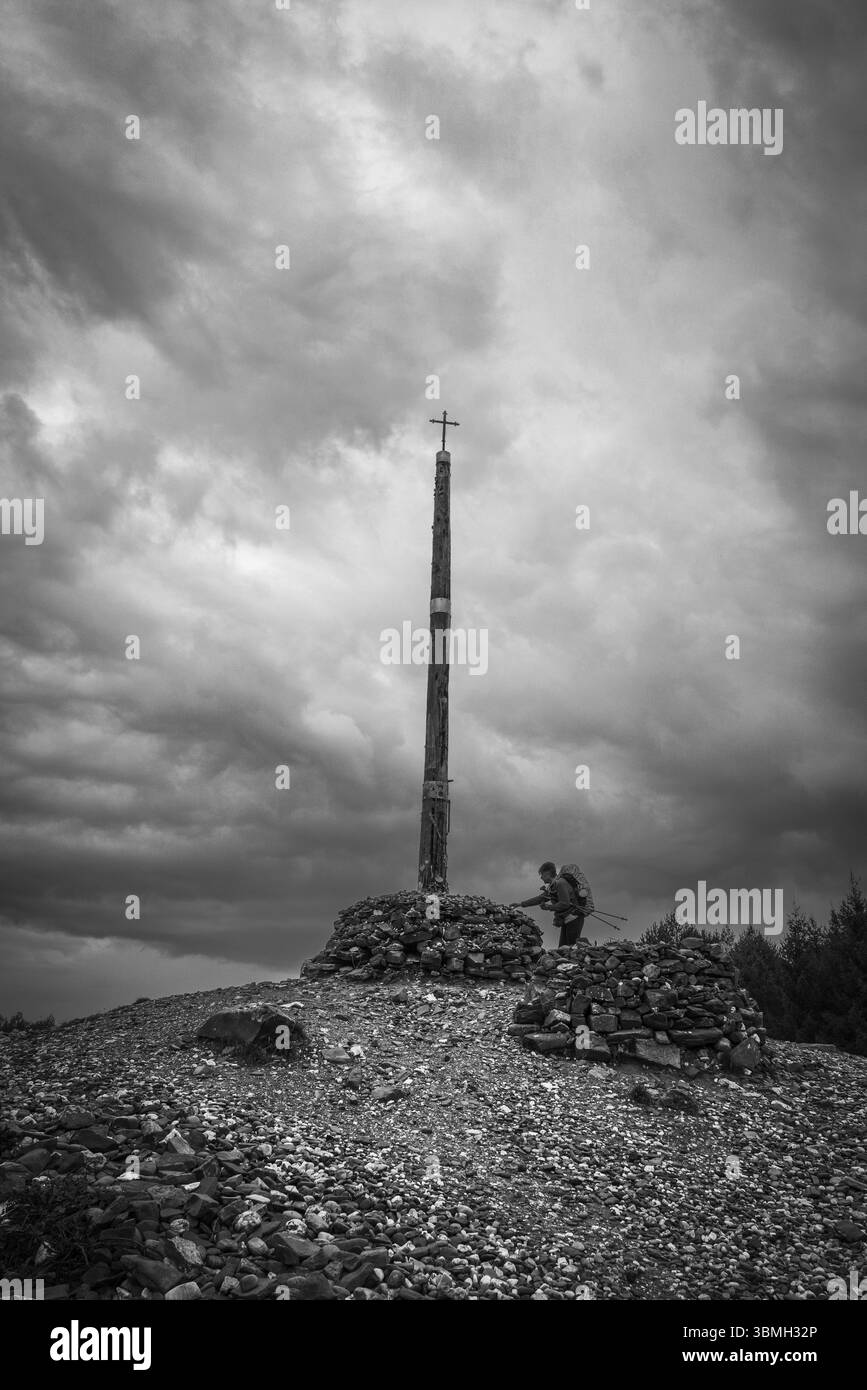 Pilger auf dem Jakobsweg mit Votivsteinen und Opfergaben in Cruz de Ferro (Eisernes Kreuz), dem Hügel Foncebadon, der Region Bierzo, Kastilien und Leo Stockfoto