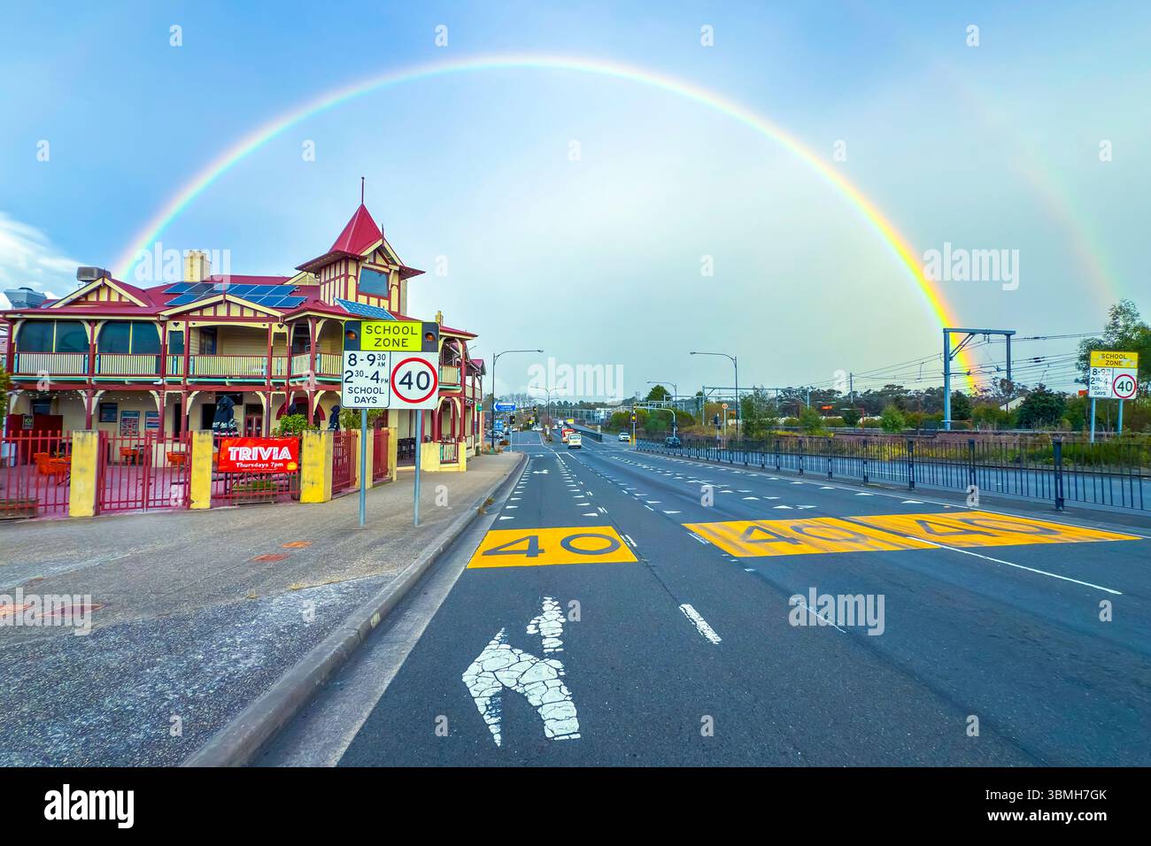 Foto von einem lebhaften Regenbogen am frühen Morgen über Gebäuden und dem Great Western Highway in der Stadt Lawson in den Blue Mountains in Australien. Stockfoto