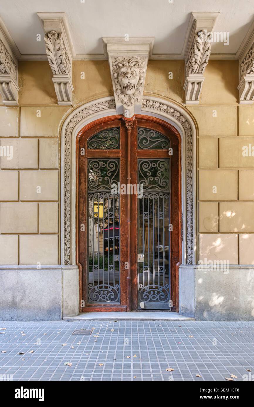 Verzierte hölzerne Eingangstür Eines klassischen Barcelona-Gebäudes mit skulpturalen Details. Historische Spanische Architektur, Städtische Fassade, Dekoratives Ele Stockfoto