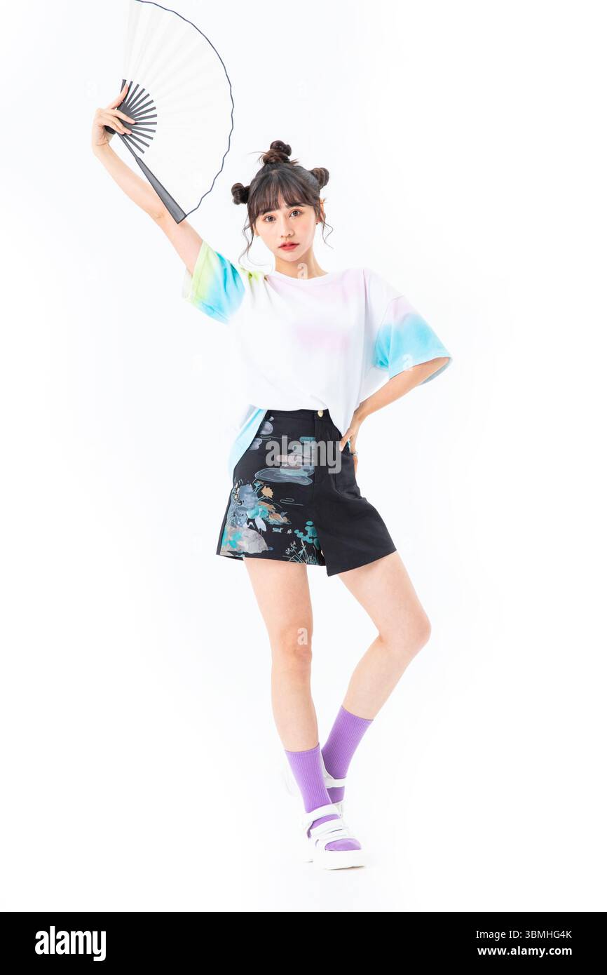 Eine schöne junge Studentin in einem kurzen Rock im chinesischen Stil hält ein traditionelles chinesisches Papier fan​ Stockfoto