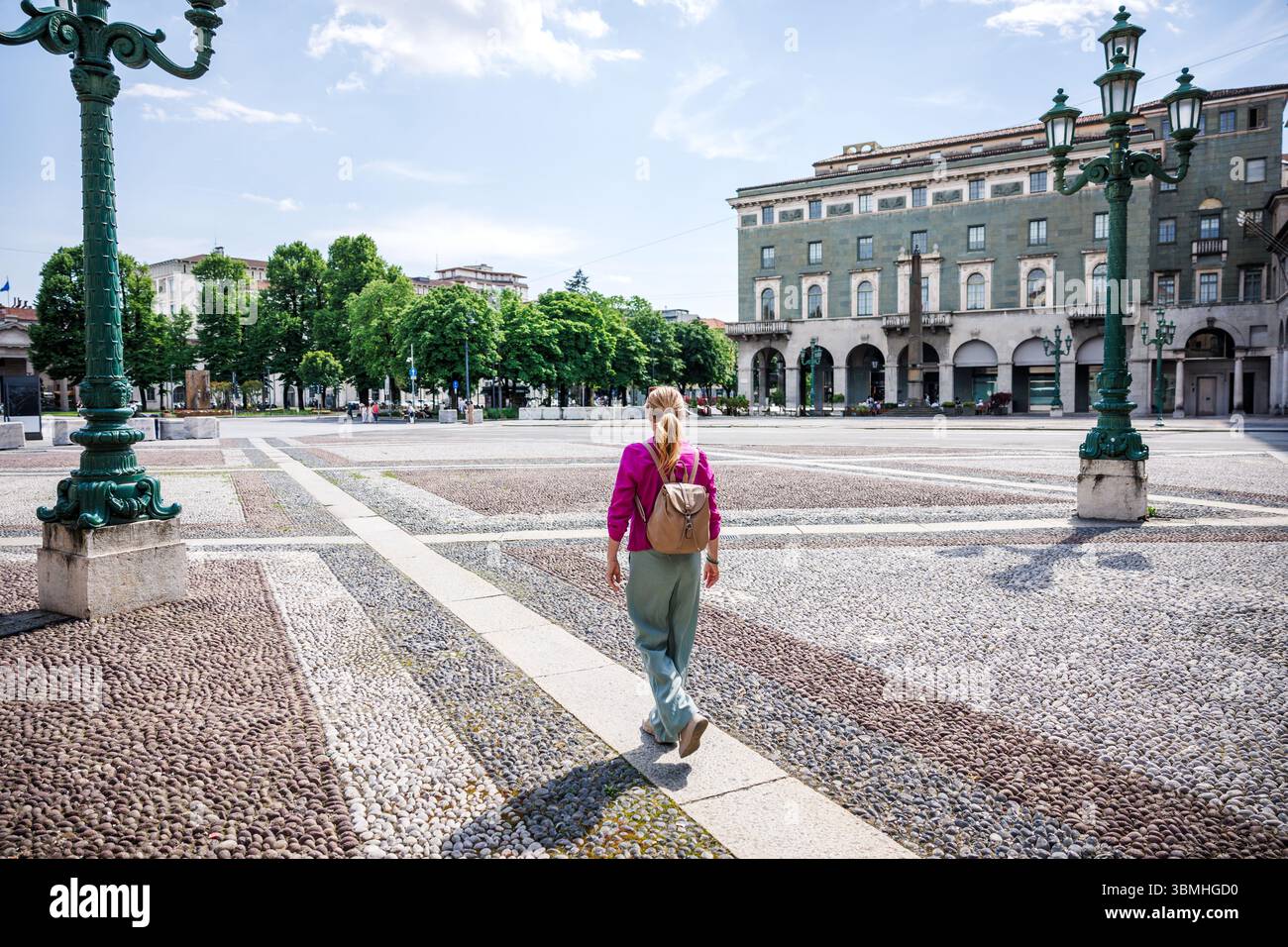 Frau, die während der Sommerferien über den sonnigen Stadtplatz Piazza Vittorio Veneto in Bergamo, Italien, spaziert. Alleinreisen in Europa Stockfoto
