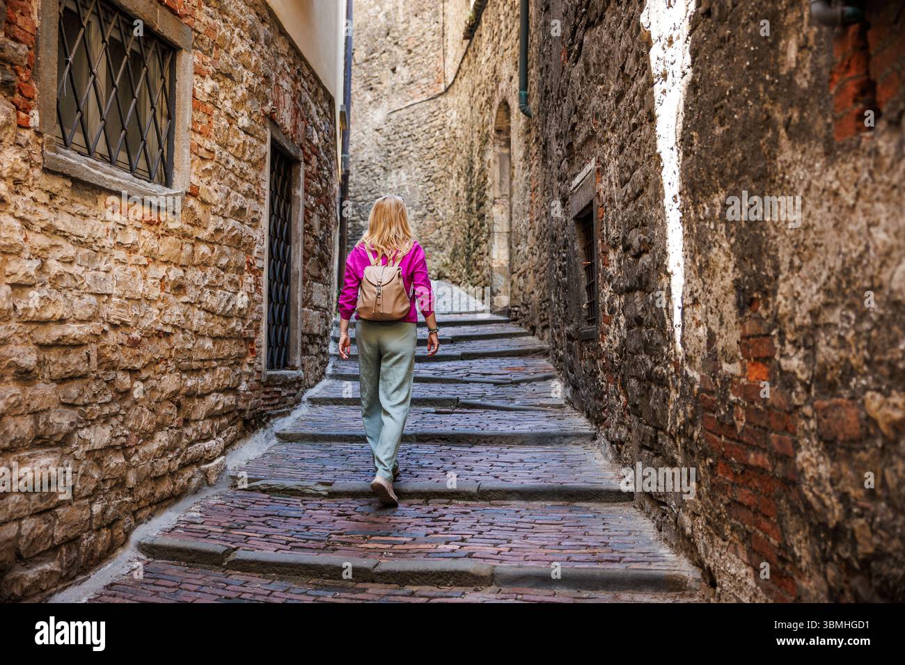 Weibliche Touristen spazieren alte Steintreppen in der historischen Altstadt Citta Alta von Bergamo, Italien. Frau, die europa alleine bereist Stockfoto