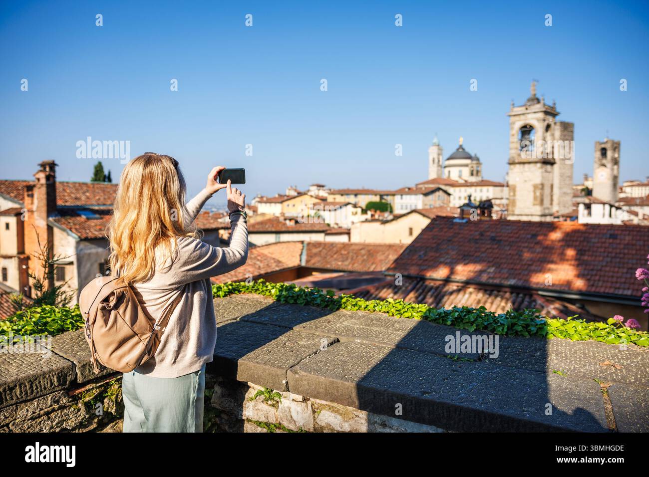 Frau fotografiert auf Smartphone-Skyline in Citta Alta, Bergamo, Italien während der Urlaubsreise. Alleinreiseurlaub in Europa Stockfoto