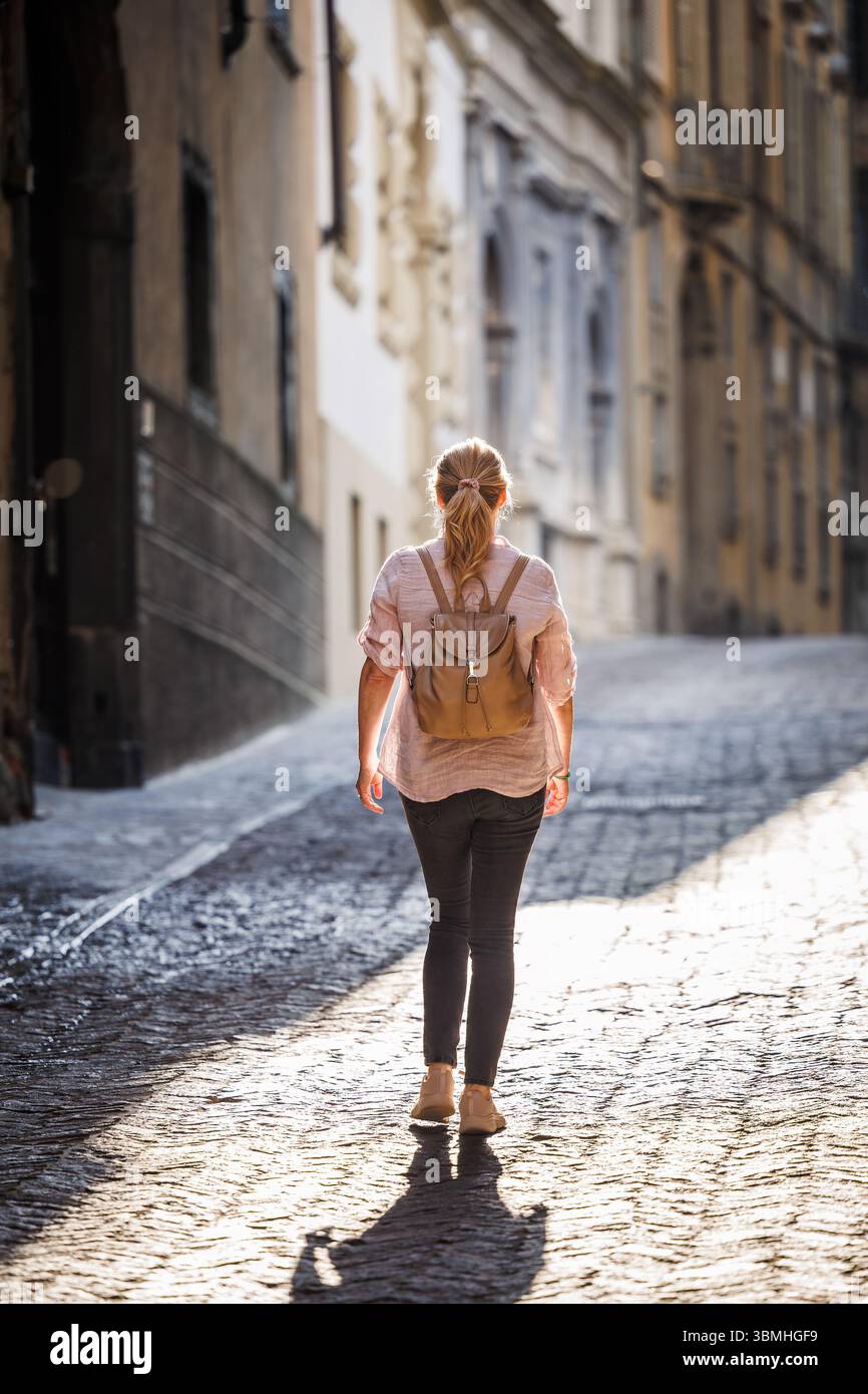 Frau, die alleine in einer engen Straße in Bergamo, Italien, unterwegs ist, während der Sommerreise allein Stockfoto