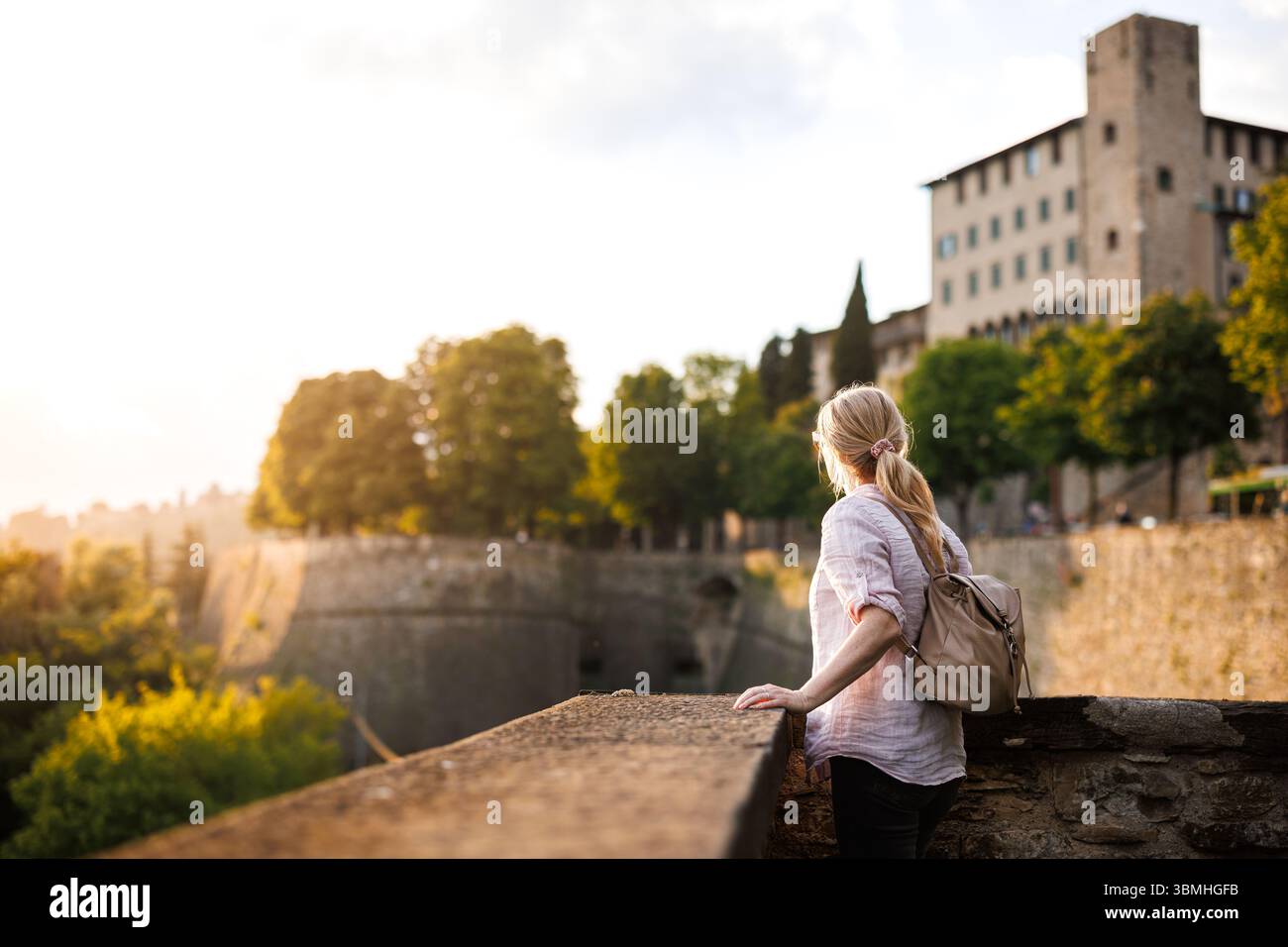Frau, die während eines Alleinreiseurlaubs in Europa den Sonnenuntergang von den venezianischen Stadtmauern von Bergamo, Italien genießt Stockfoto