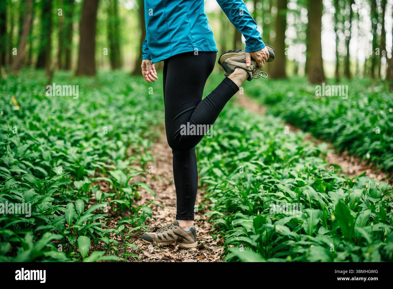 Stretchläuferin greift Knöchel im Wald, Sportbekleidung und Fitnessvorbereitung im Freien. Vorbereitung zum Laufen Stockfoto