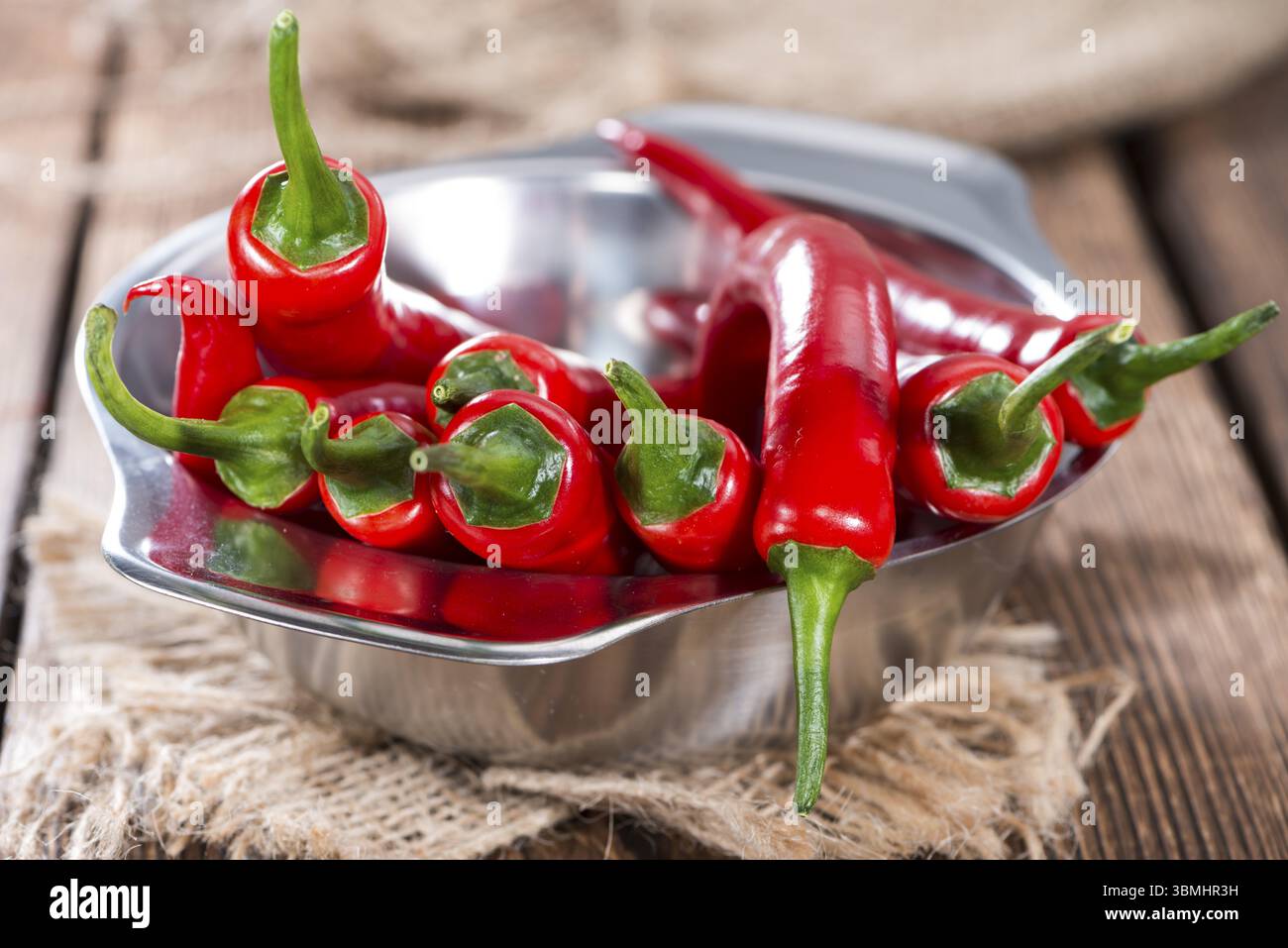 Kleine Schale mit roten Chilischoten auf hölzernen Hintergrund Stockfoto
