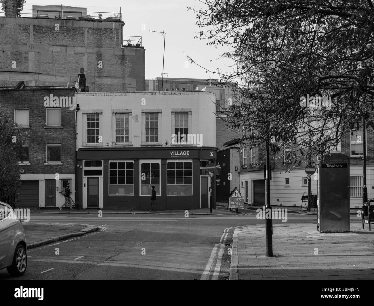 Vereinigtes Königreich, London, 4. Juli 2025. Schwarz-weiß-Blick auf eine ruhige Londoner Straßenecke mit dem Village Pub und den umliegenden Gebäuden Stockfoto