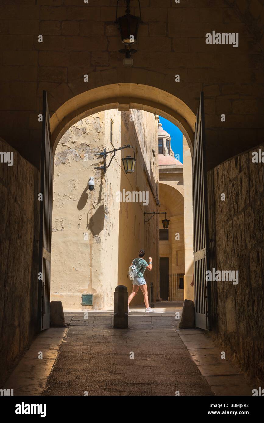 Weibliche Reise, Blick auf eine junge Frau im Rucksack, die allein die engen Gassen der historischen ummauerten Stadt Mdina, Malta, erkundet. Stockfoto