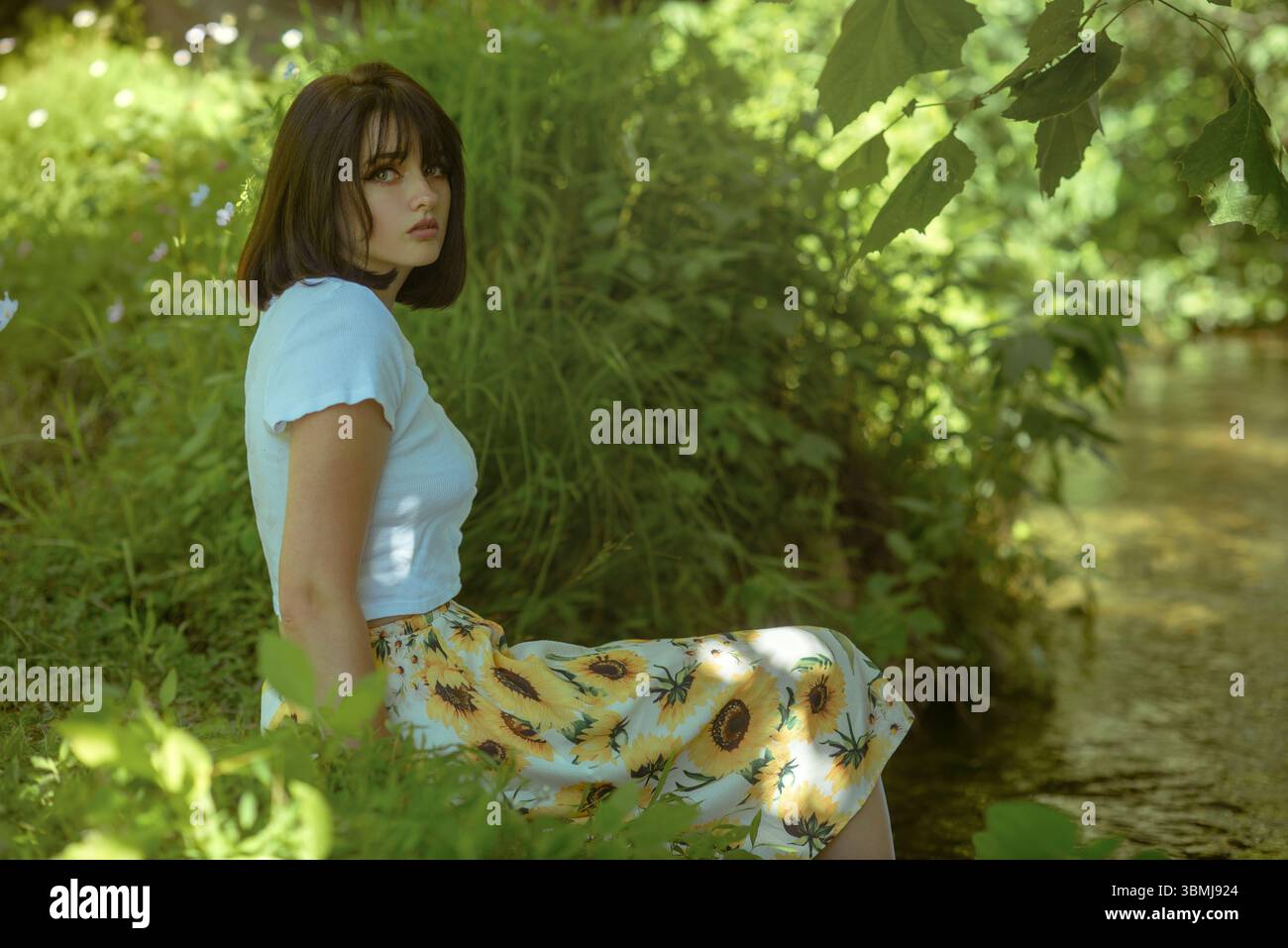 Schöne Frau, die an einem Creek sitzt Stockfoto