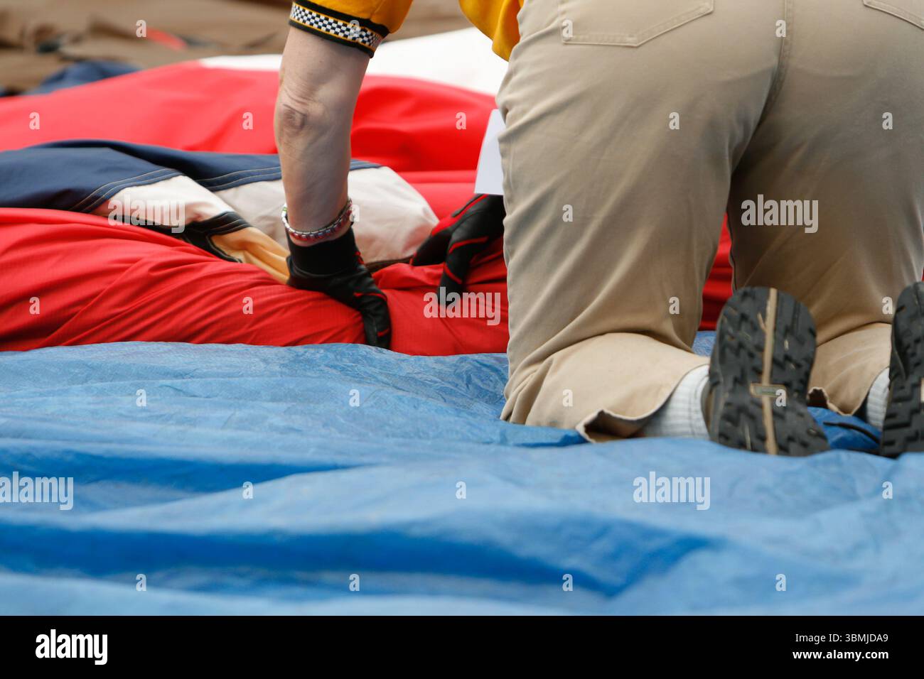 Freiwillige tragen Handschuhe, die nach einer Veranstaltung vorsichtig eine große Flagge falten Stockfoto