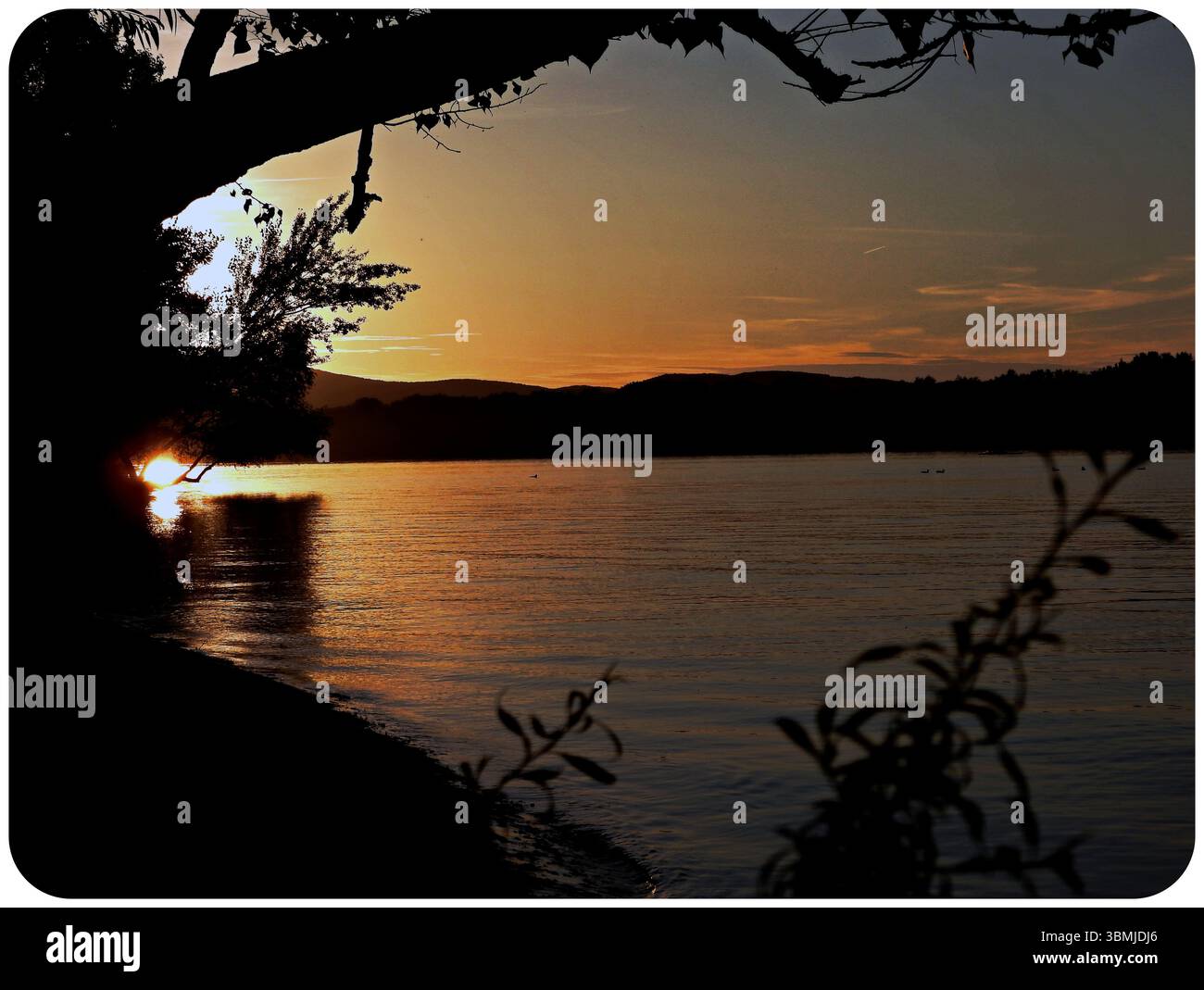 Malerischer Sonnenuntergang über der Donau mit Bergsilhouetten, aufgenommen während eines Campingausflugs Stockfoto